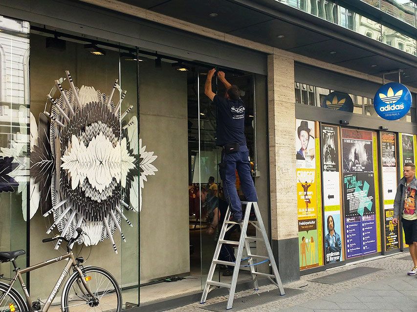 ISM Mitarbeiter steht auf einer Leitung und arbeitet an Glasfront